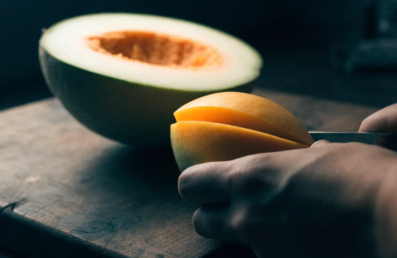 Kantalupa i prerezani mango na mat crnoj ploči